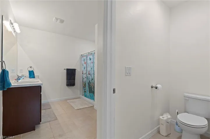 Full bath featuring vanity, light tile patterned floors, and a shower with curtain