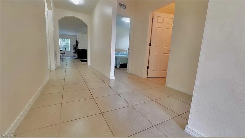 Corridor featuring arched walkways and light tile patterned floors