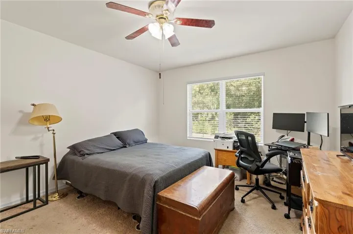 Bedroom with light carpet, a desk, and ceiling fan
