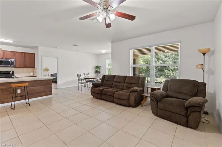 Living area featuring light tile patterned floors and a ceiling fan