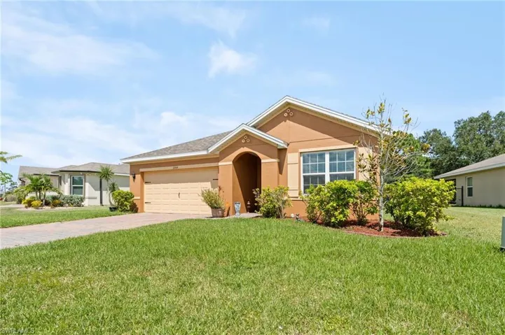 Ranch-style home with stucco siding, driveway, a front lawn, and a garage