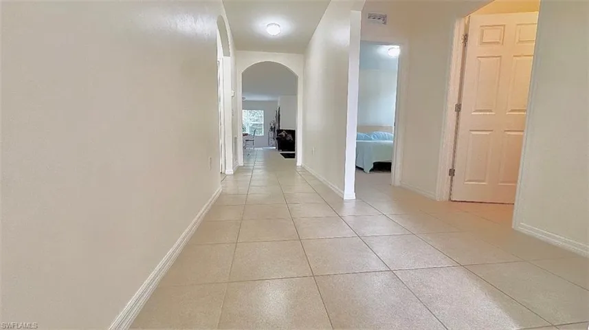 Corridor with arched walkways and light tile patterned floors