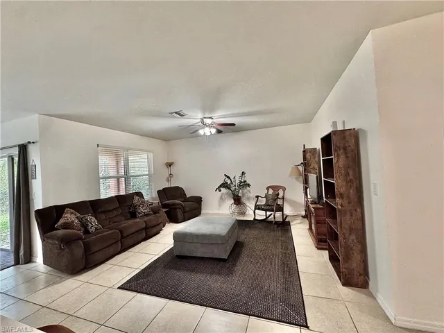 Living area featuring a ceiling fan and light tile patterned floors