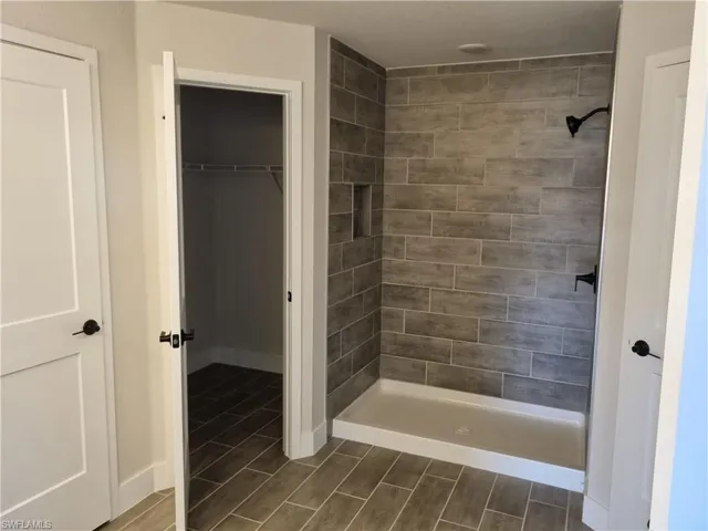 Full bath with wood finish floors, a stall shower, and a walk in closet