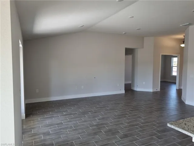 Unfurnished room with wood tiled floors and lofted ceiling