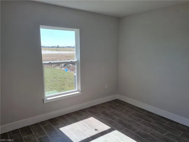 Spare room featuring baseboards and wood finish floors