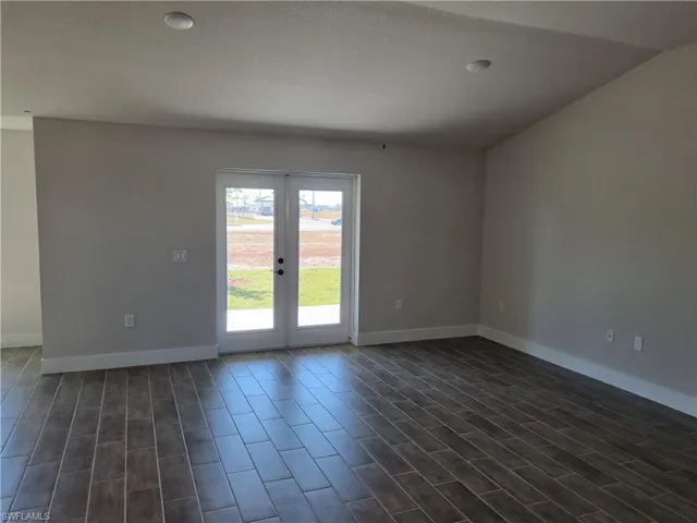 Empty room with dark wood finished floors, a textured ceiling, and french doors