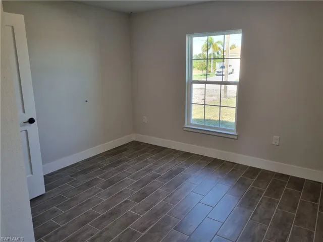 Spare room featuring baseboards and wood tiled floors