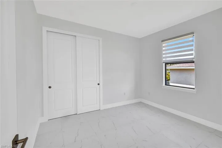 Unfurnished bedroom with light marble finish flooring and a closet