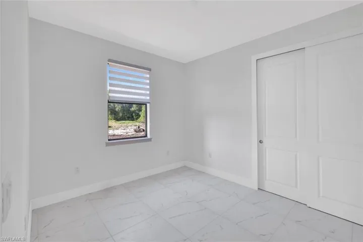 Unfurnished bedroom with light marble finish flooring and a closet