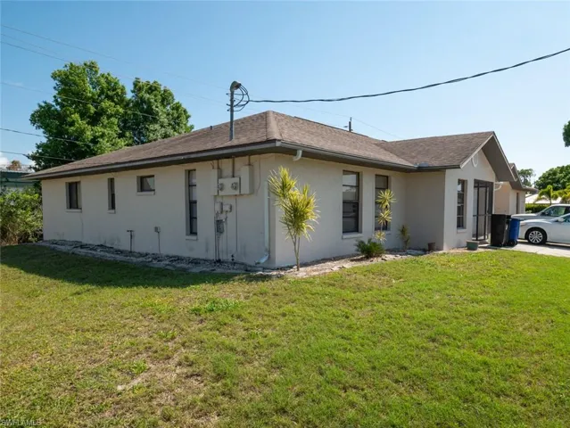 View of side of home featuring stucco siding, a yard, and roof with shingles