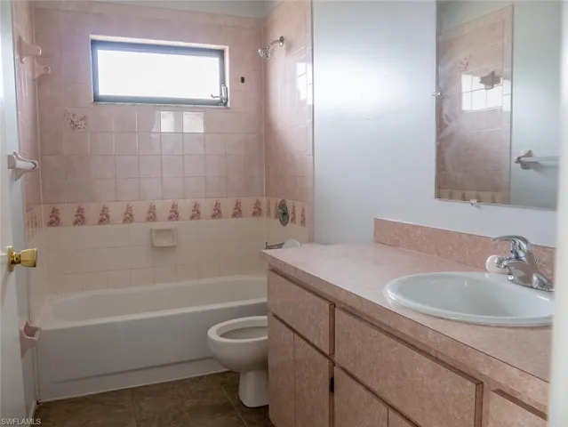 Full bathroom featuring bathing tub / shower combination, vanity, and dark tile patterned floors