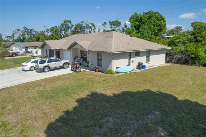 View of front of property with a front yard, stucco siding, roof with shingles, and concrete driveway