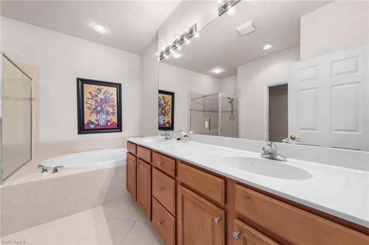 Full bath featuring a stall shower, double vanity, light tile patterned floors, a garden tub, and recessed lighting