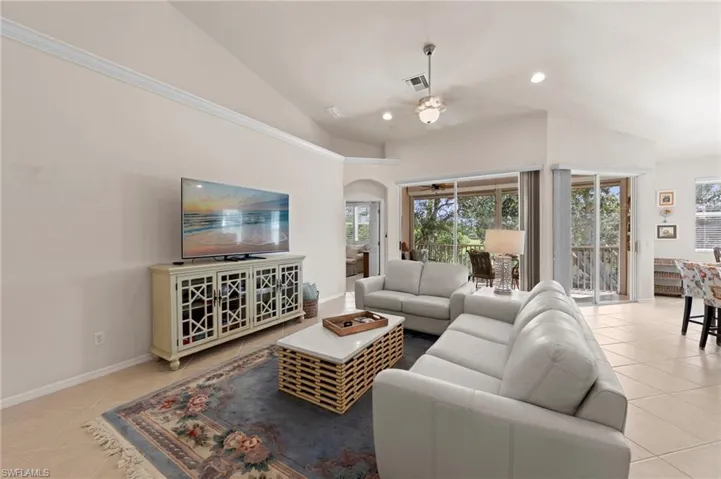 Living area featuring light tile patterned floors, recessed lighting, arched walkways, ceiling fan, and high vaulted ceiling