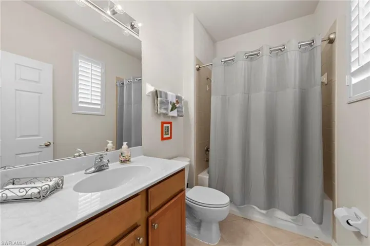 Full bathroom featuring shower / bath combo, vanity, and light tile patterned floors