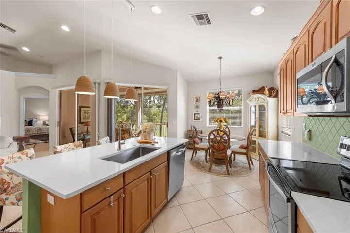 Kitchen featuring brown cabinets, stainless steel appliances, recessed lighting, tasteful backsplash, and pendant lighting