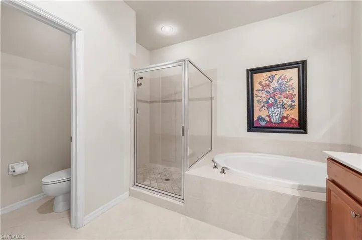 Bathroom featuring vanity, a stall shower, a bath, and light tile patterned floors