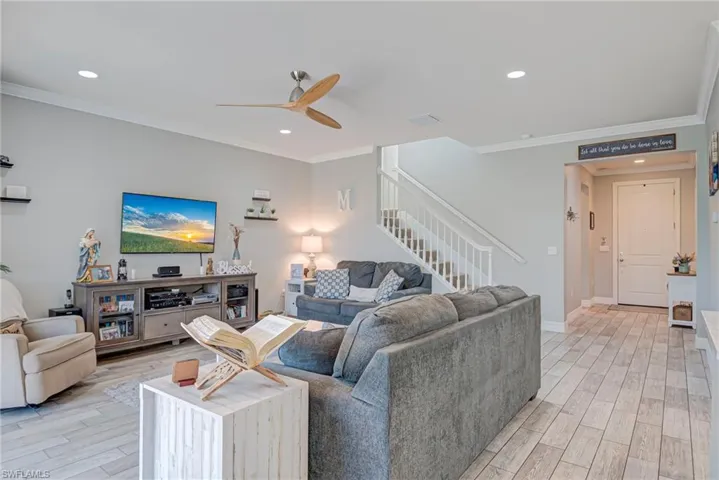 Living room with plank tile floors, crown molding, a ceiling fan, and recessed lighting