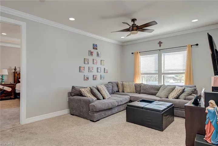 Carpeted loft with a ceiling fan, ornamental molding, and recessed lighting