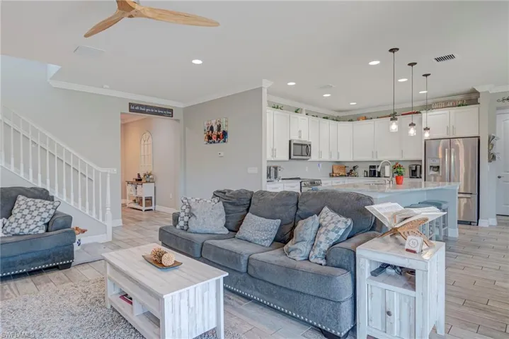 Living room with plank tile flooring, a ceiling fan, recessed lighting, and crown molding