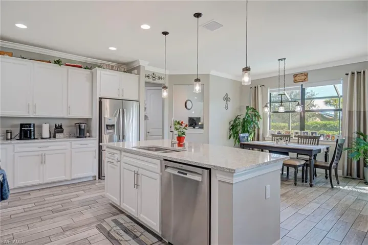 Kitchen featuring stainless steel appliances, white cabinets, pendant lighting, and crown molding