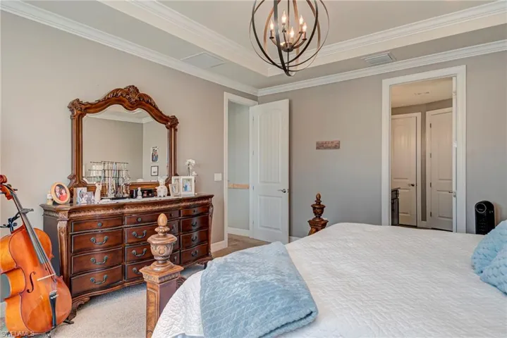 Carpeted bedroom featuring a chandelier and ornamental molding