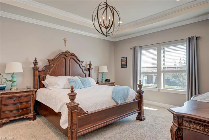 Carpeted bedroom featuring hanging lights and crown molding