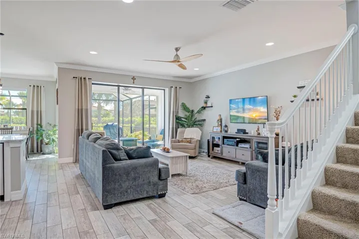 Living area with plank tile floors, ceiling fan, crown molding, healthy amount of natural light, and recessed lighting
