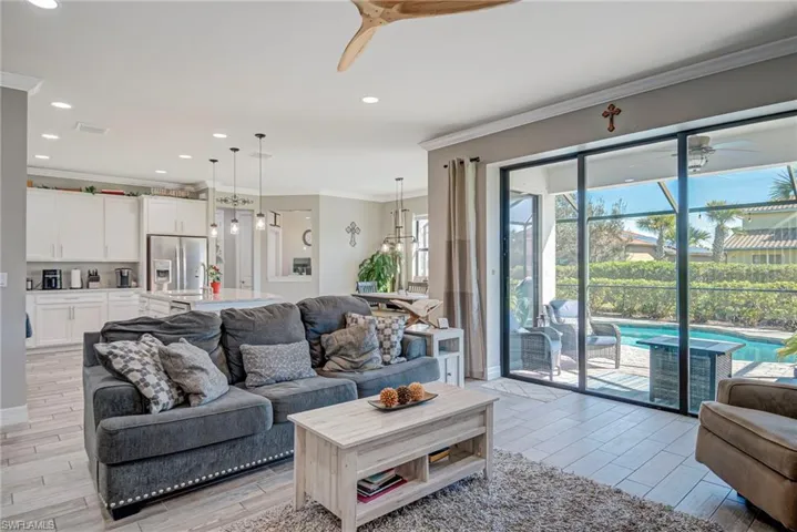 Living area featuring ceiling fan, ornamental molding, plank tile floors, and recessed lighting