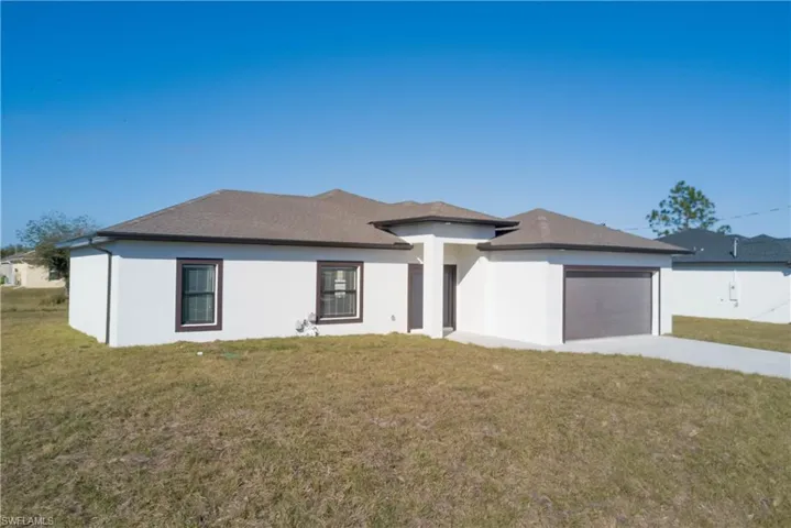 Prairie-style home with a front yard, concrete driveway, stucco siding, and an attached garage
