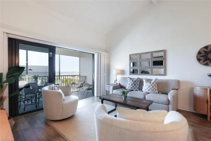 Living room featuring wood finished floors, high vaulted ceiling, a water view, and beamed ceiling