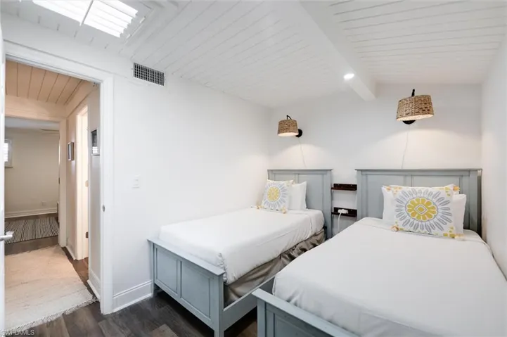 Bedroom with dark wood-type flooring and a wooden ceiling with exposed beams