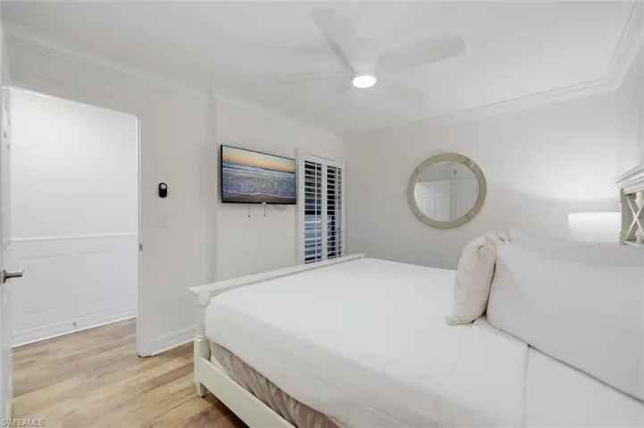 Bedroom featuring light wood-style floors, crown molding, and a ceiling fan