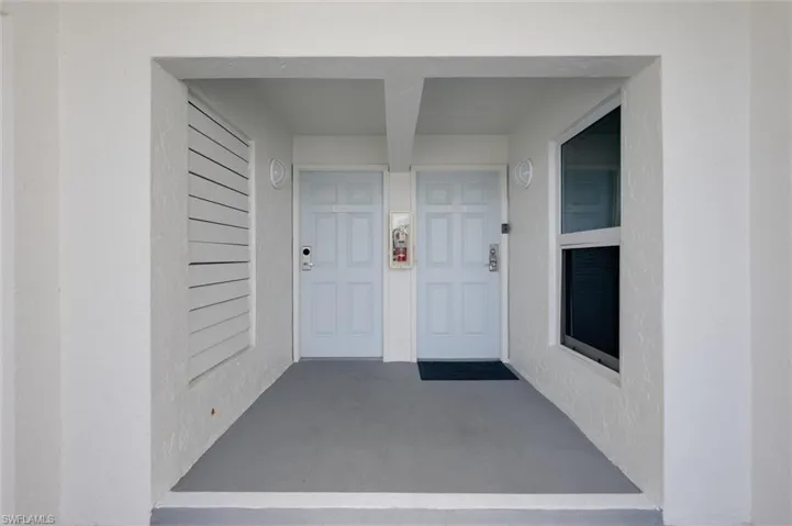 Entrance to property with covered porch and stucco siding