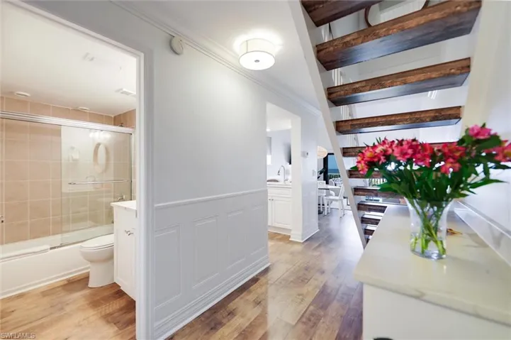 Hallway with a wainscoted wall, light wood-style flooring, a decorative wall, and crown molding