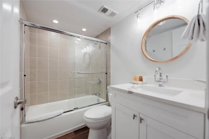 Full bathroom with vanity, bath / shower combo with glass door, recessed lighting, and dark wood finished floors