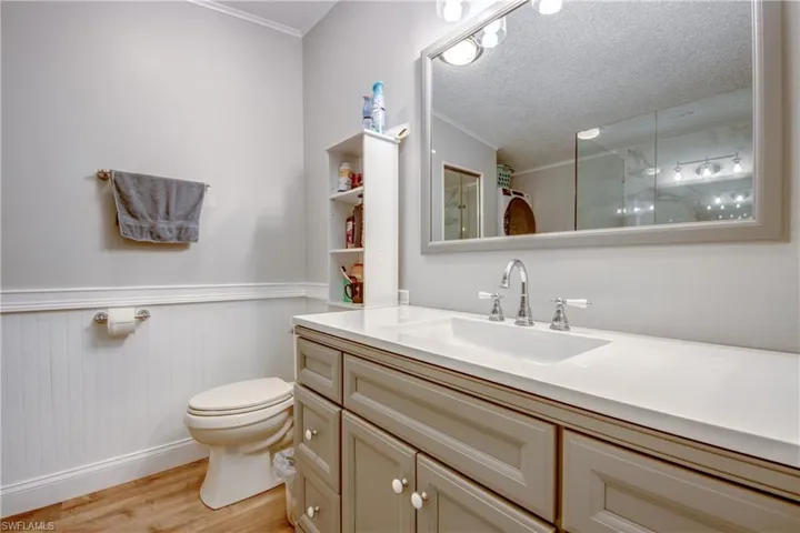 Bathroom featuring light wood-style flooring, a textured ceiling, vanity, crown molding, and a shower with curtain