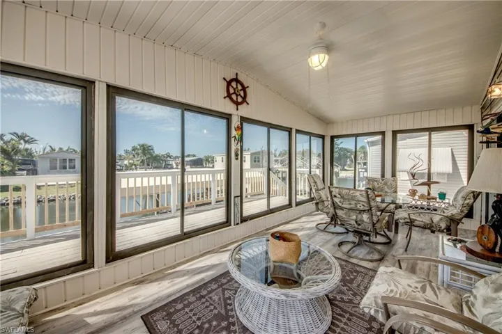 Sunroom / solarium with a water view, lofted ceiling, and wood finished floors