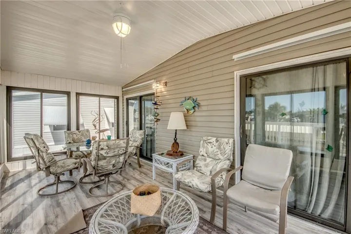 Sunroom / solarium featuring lofted ceiling, wood finished floors, and wooden walls