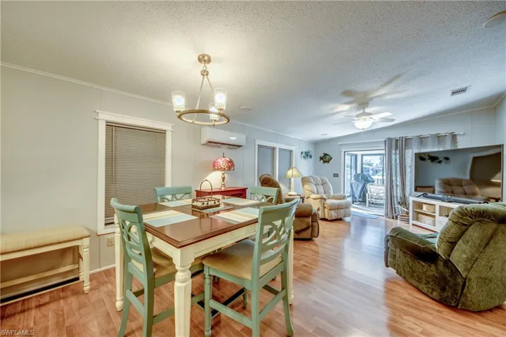 Dining space with a textured ceiling, light wood-style flooring, ceiling fan, an AC wall unit, and a chandelier