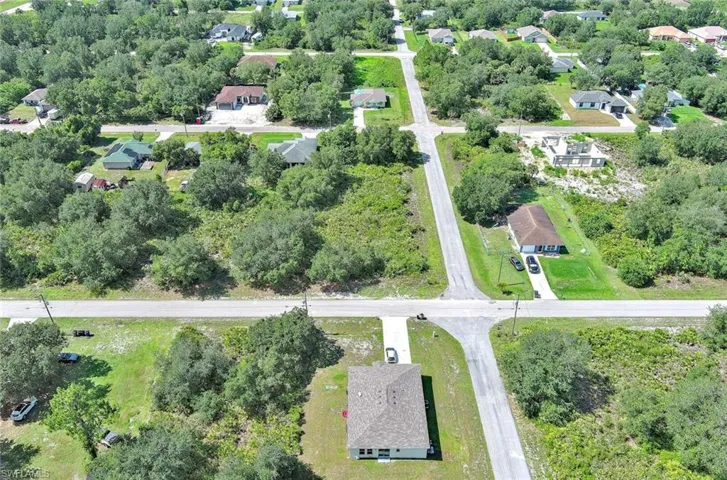 Aerial view of property's location with nearby suburban area and a tree filled landscape