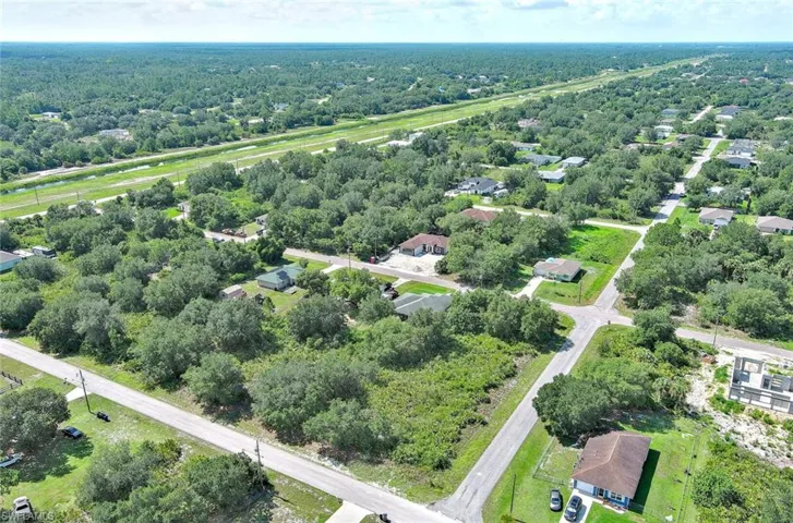Aerial overview of property's location featuring nearby suburban area and a heavily wooded area