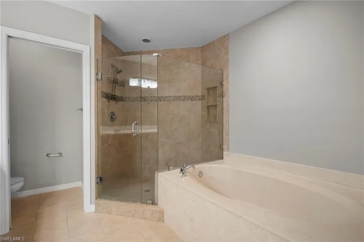 Full bathroom featuring a stall shower, a bath, and tile patterned flooring