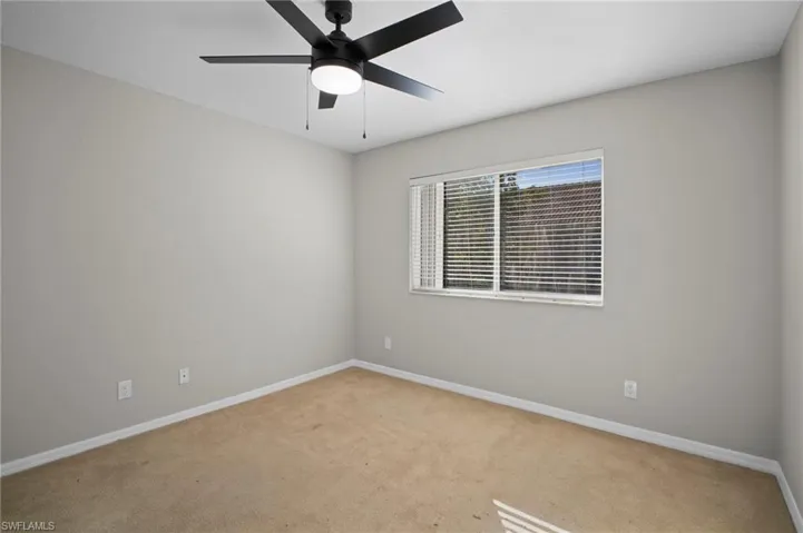 Carpeted empty room featuring baseboards and a ceiling fan