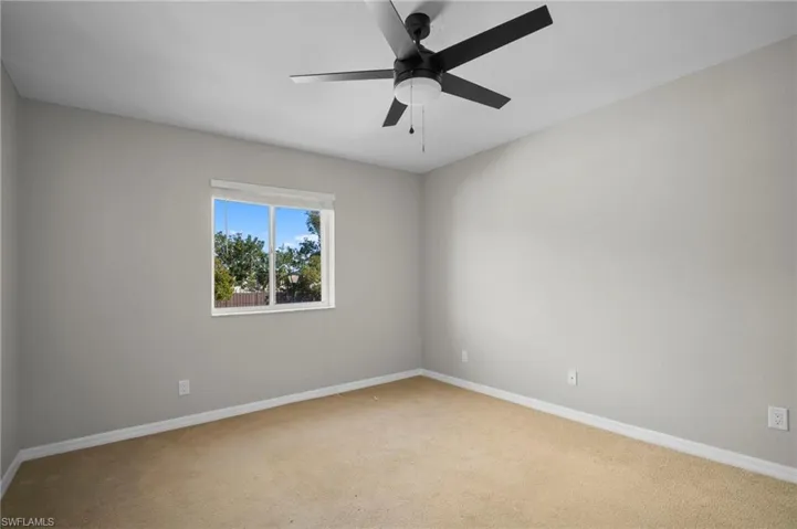 Carpeted spare room featuring baseboards and a ceiling fan
