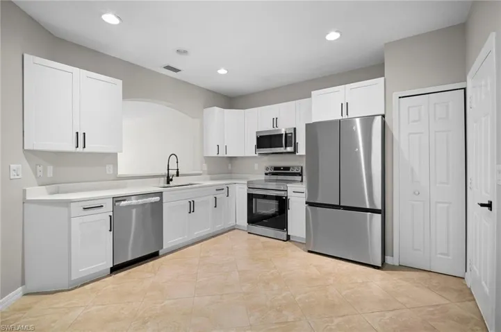 Kitchen featuring stainless steel appliances, white cabinetry, recessed lighting, and light tile patterned floors