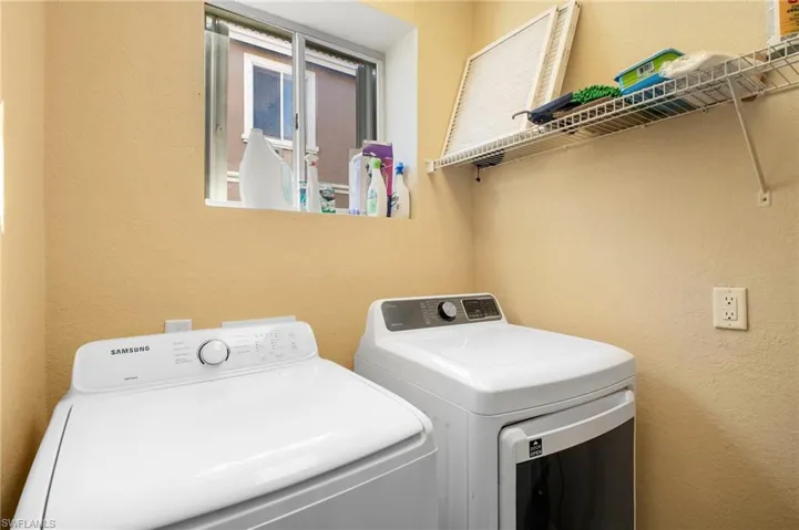 Laundry area with a textured wall and washer and dryer