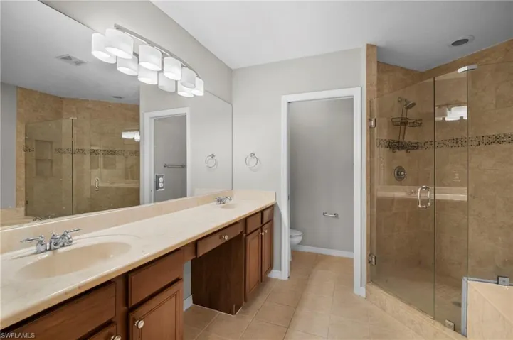 Bathroom with a stall shower, double vanity, and light tile patterned floors