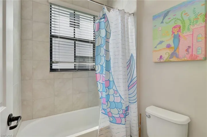 Jack/Jill bathroom with shower / tub combo with curtain and toilet